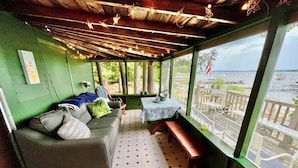 Una habitación acogedora con un sofá, una mesita y un banco. Tiene vista a un cuerpo de agua y un muelle.