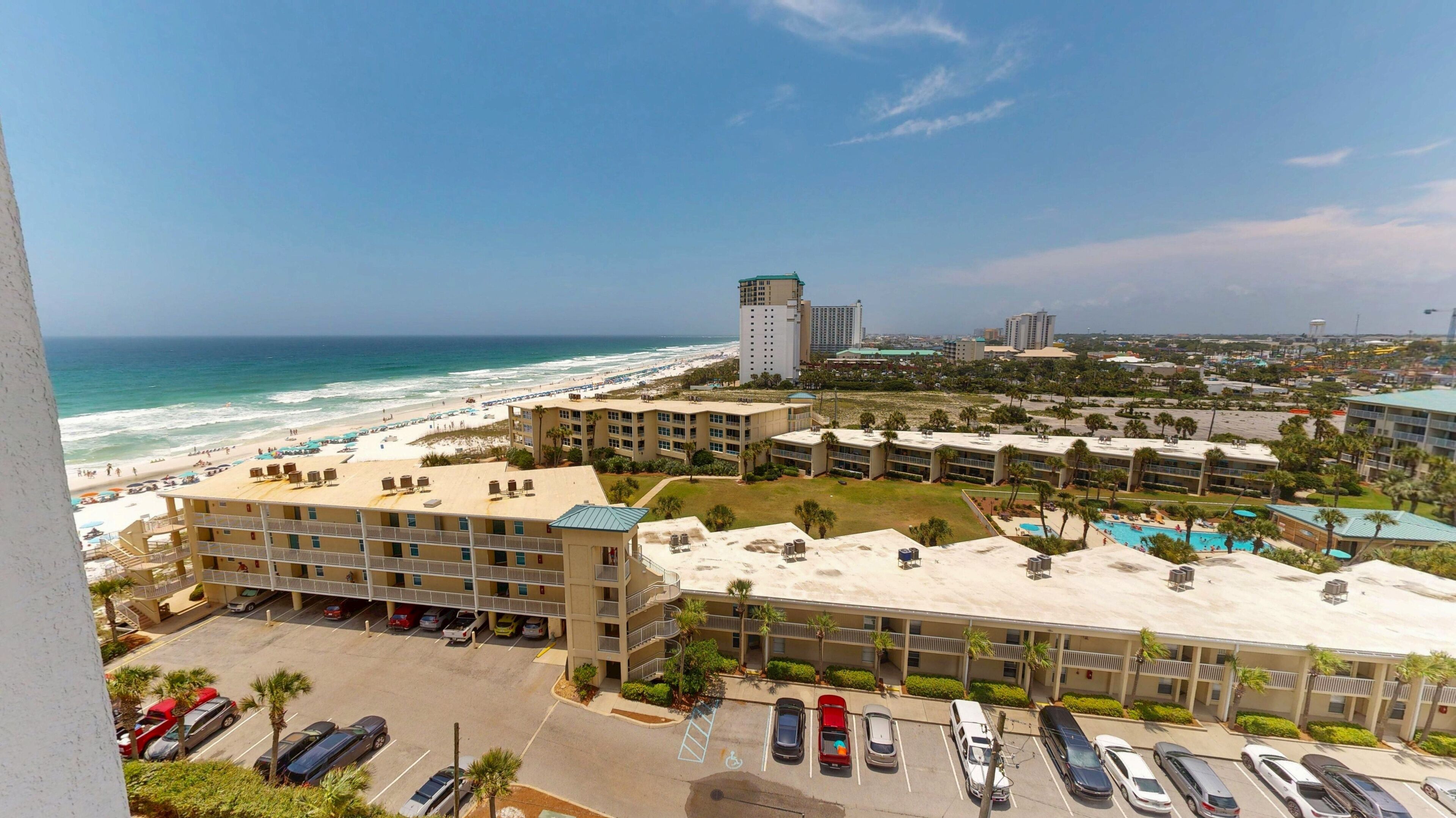 A hotel with a rooftop pool, a parking lot, and a view of the beach and ocean.