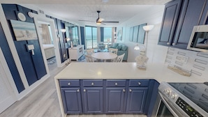 Una cocina moderna con una isla central, armarios empotrados, una zona de comedor con una mesa redonda y un amplio ventanal con vistas.