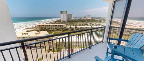 A balcony with a view of a beach and buildings.