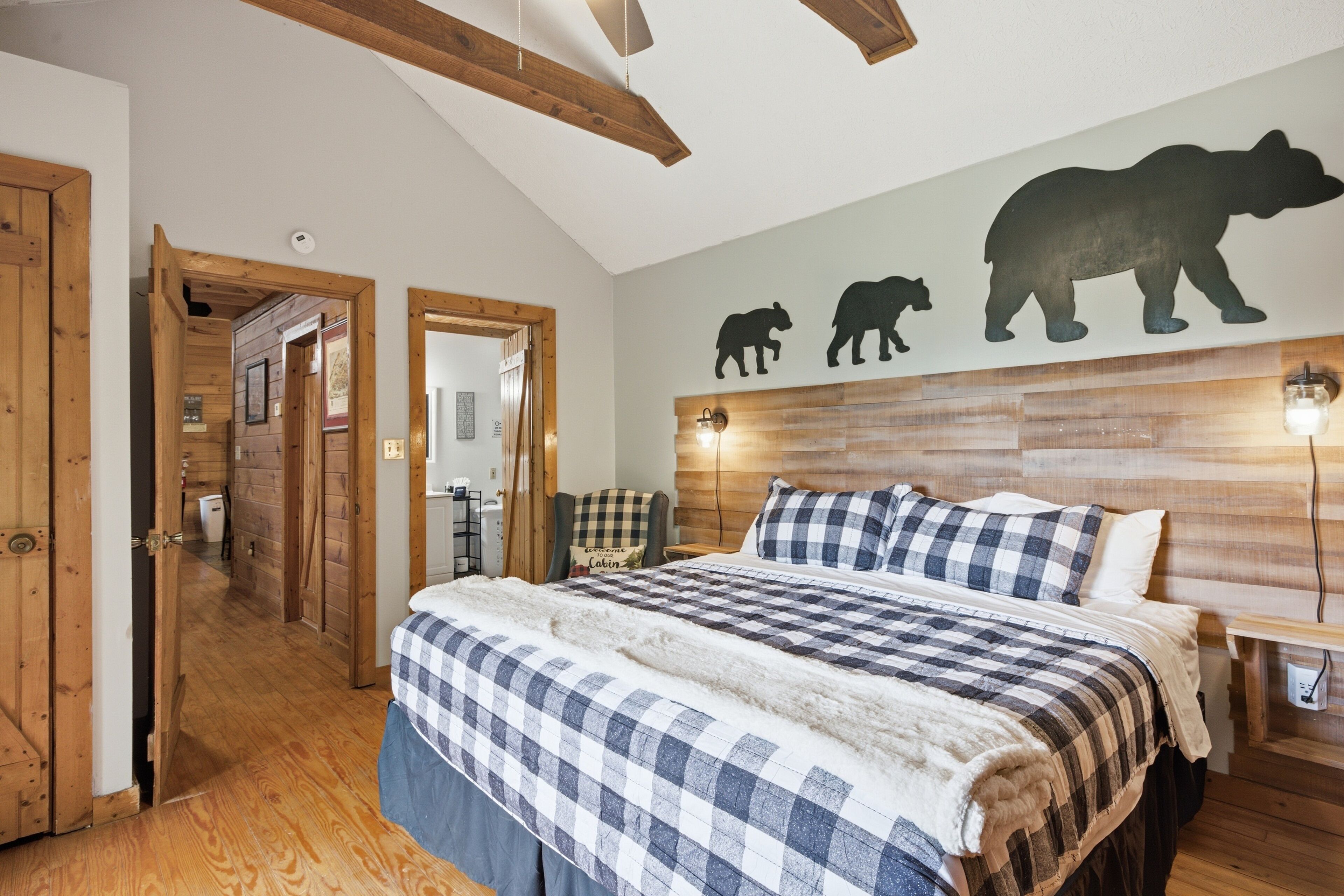 Une chambre à coucher avec une couvre-lit à carreaux, une tête de lit en bois et des appliques murales.