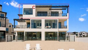 A modern multi-story building with a balcony, large windows, and a beach view. - Barefoot Beach House C 3 Bedroom Condo (St. George)