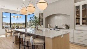 A modern kitchen with a large island, bar stools, pendant lighting, and a view of the outdoors. - Barefoot Beach House C 3 Bedroom Condo (St. George)