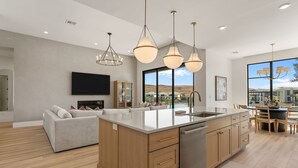 A modern kitchen with a large island, wooden cabinets, and pendant lighting. - Barefoot Beach House C 3 Bedroom Condo (St. George)