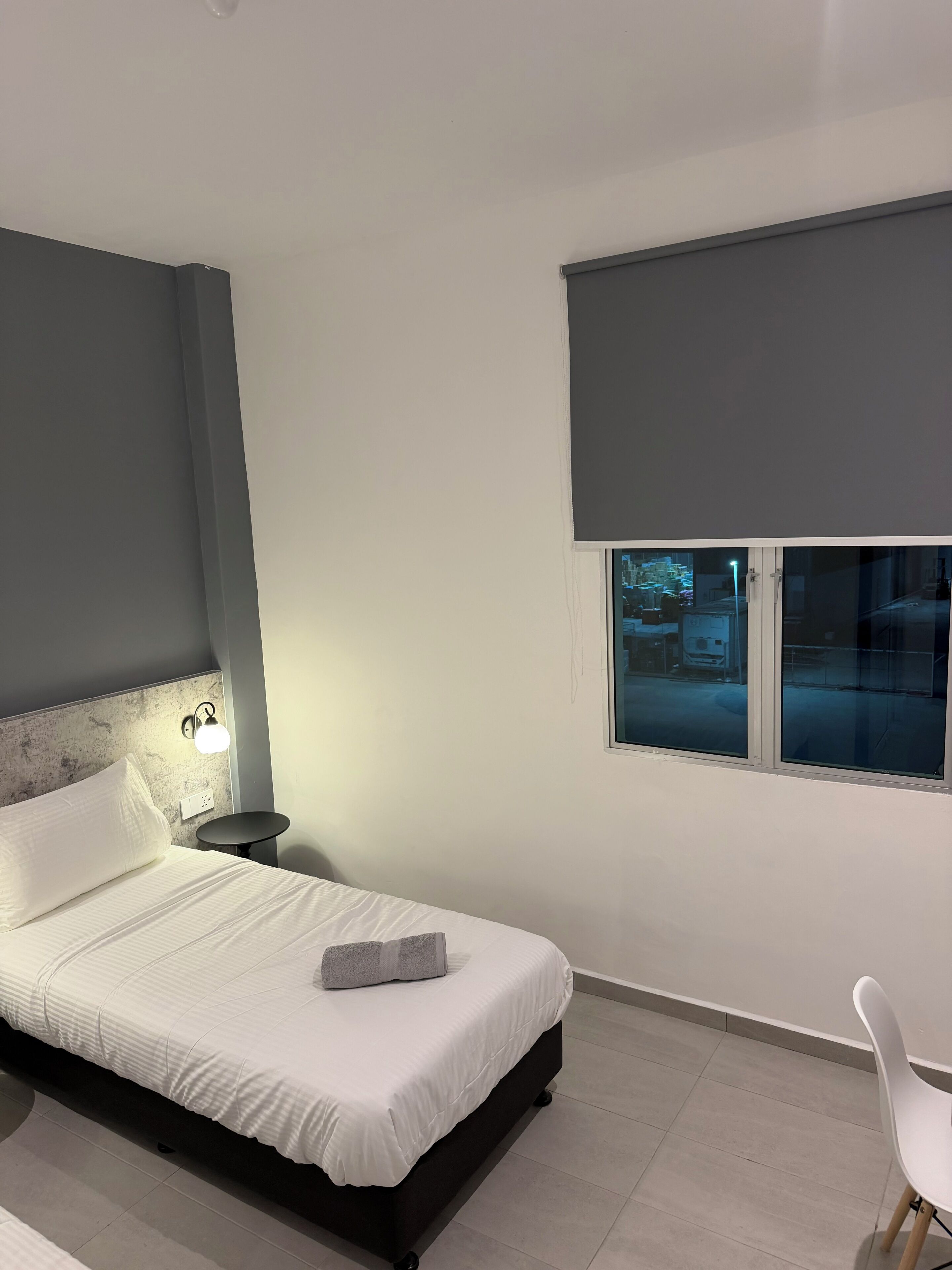 Une chambre à coucher moderne avec un lit, une lampe de chevet, une fenêtre et une chaise.