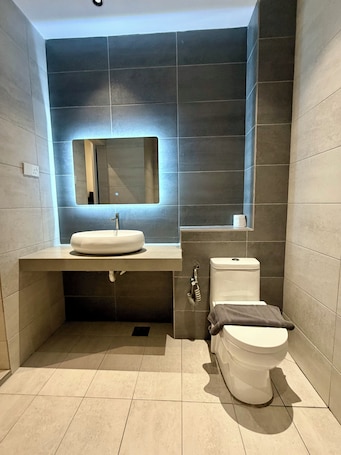 A modern bathroom with a sink, mirror, toilet, and a towel rack.. Fat Mom Room & Stay