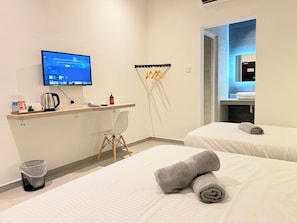 A hotel room with a desk, a television, two beds, a bathroom, and a trash bin. - Fat Mom Room & Stay (Langkawi)