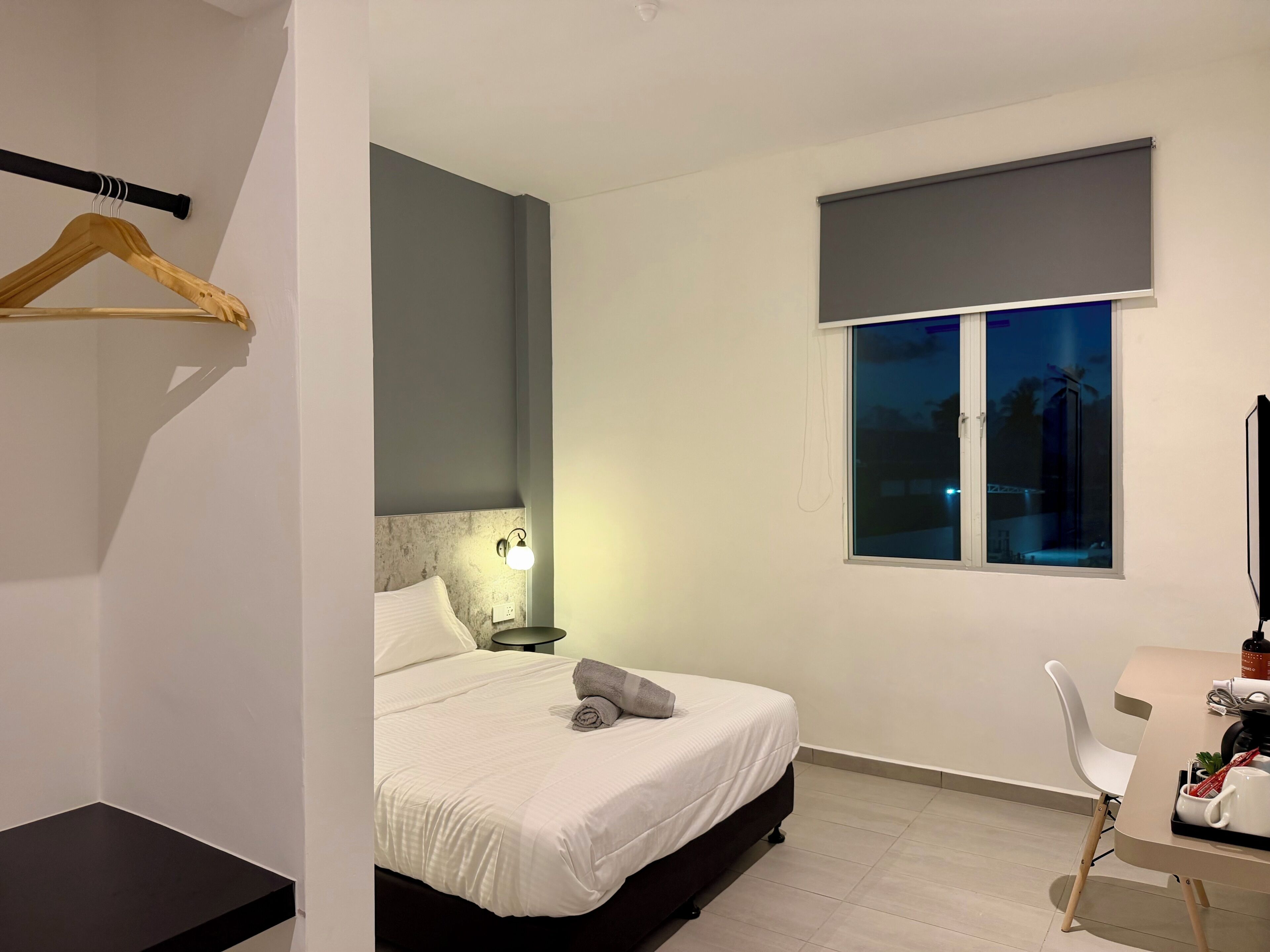 A modern bedroom with a bed, bedside table, lamp, and a window with a view.