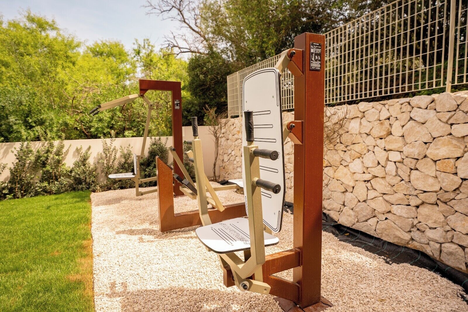 Outdoor exercise equipment, a stone wall, and a metal fence.