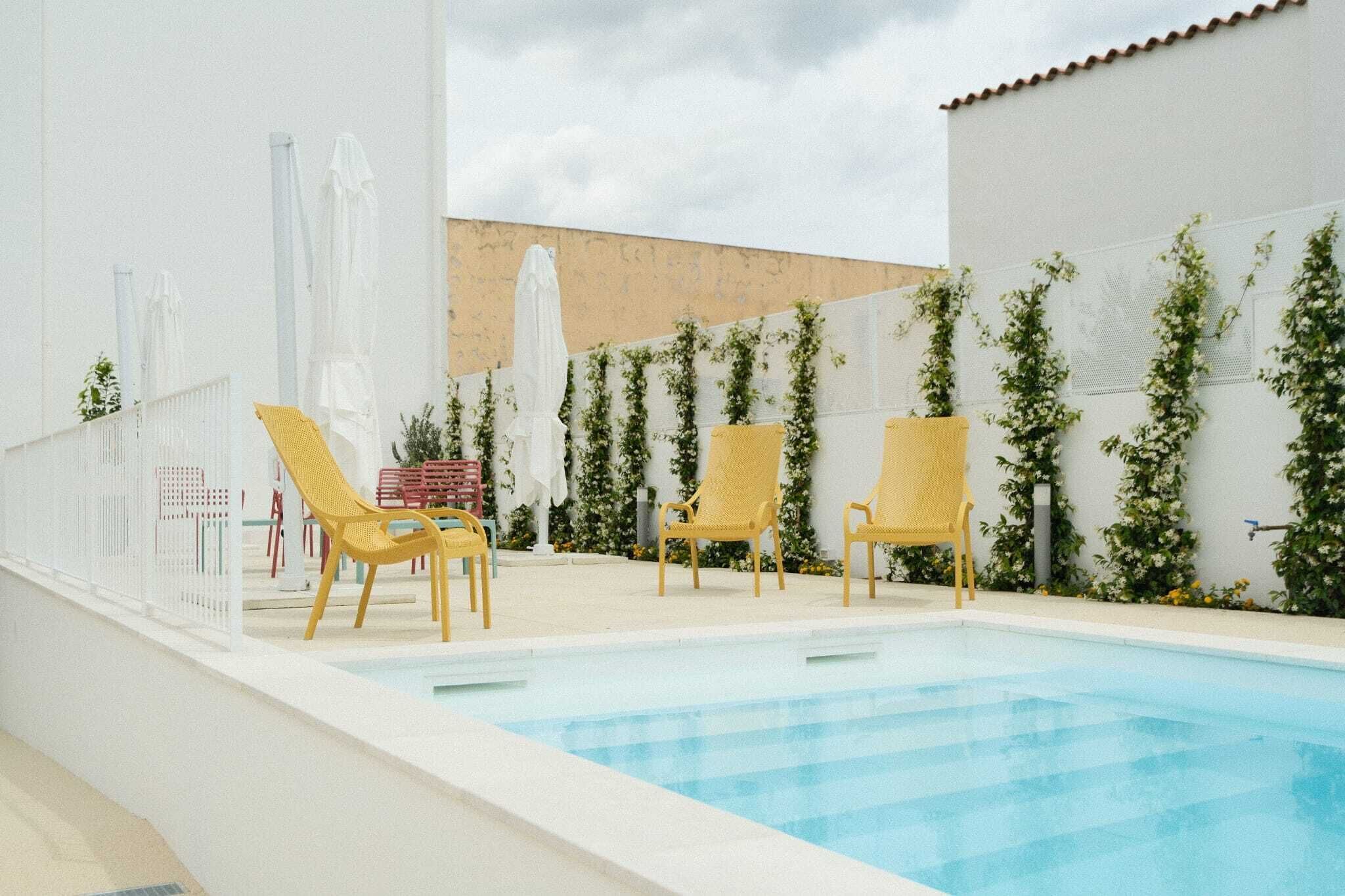 Una piscina al aire libre, sombrillas, sillones reclinables de piscina