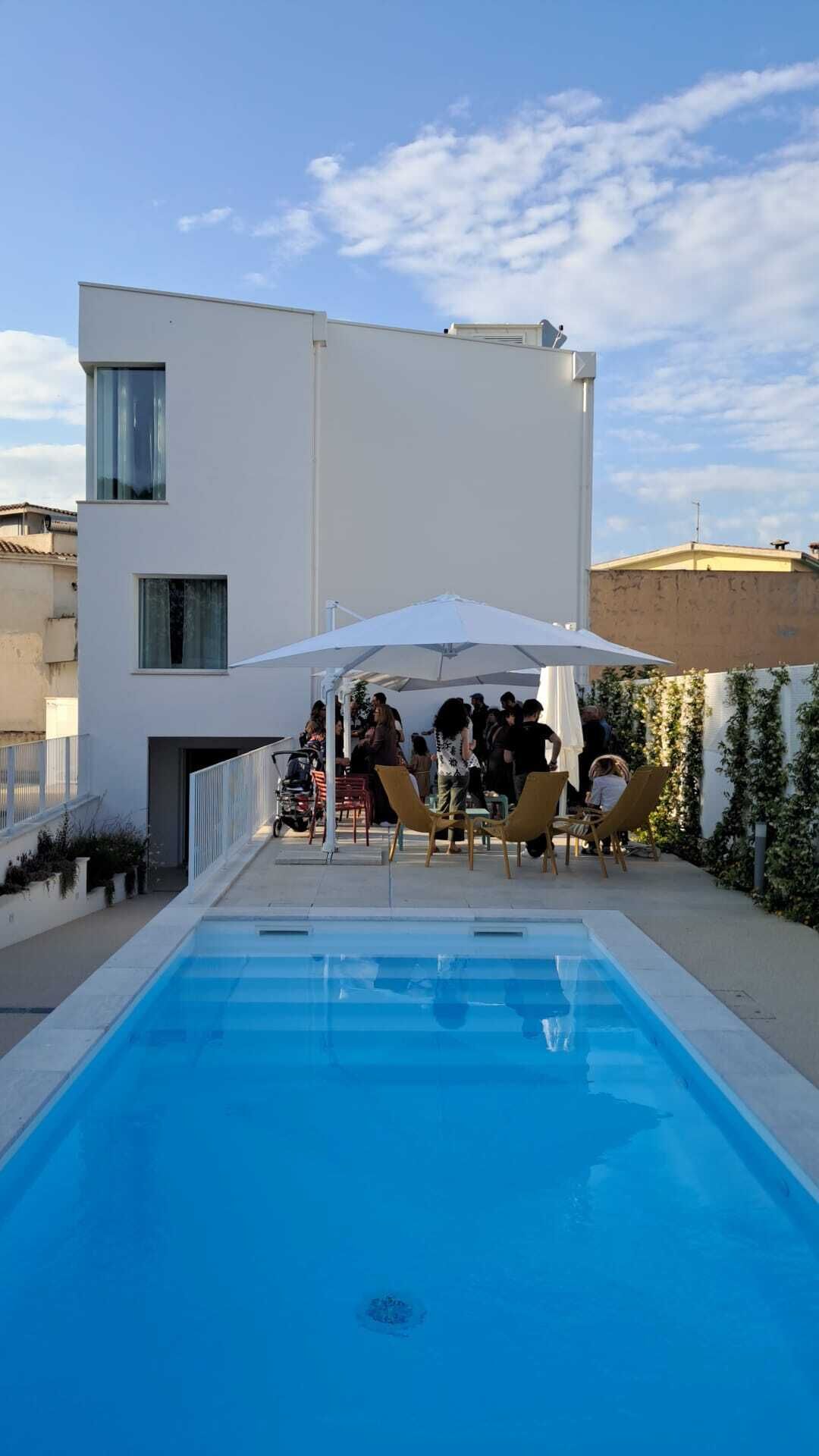 A modern building with a swimming pool, outdoor seating, and a covered area.