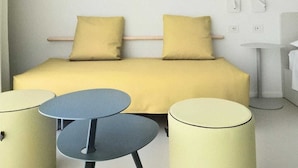 A minimalist room with a bed, two small tables, and a lamp.