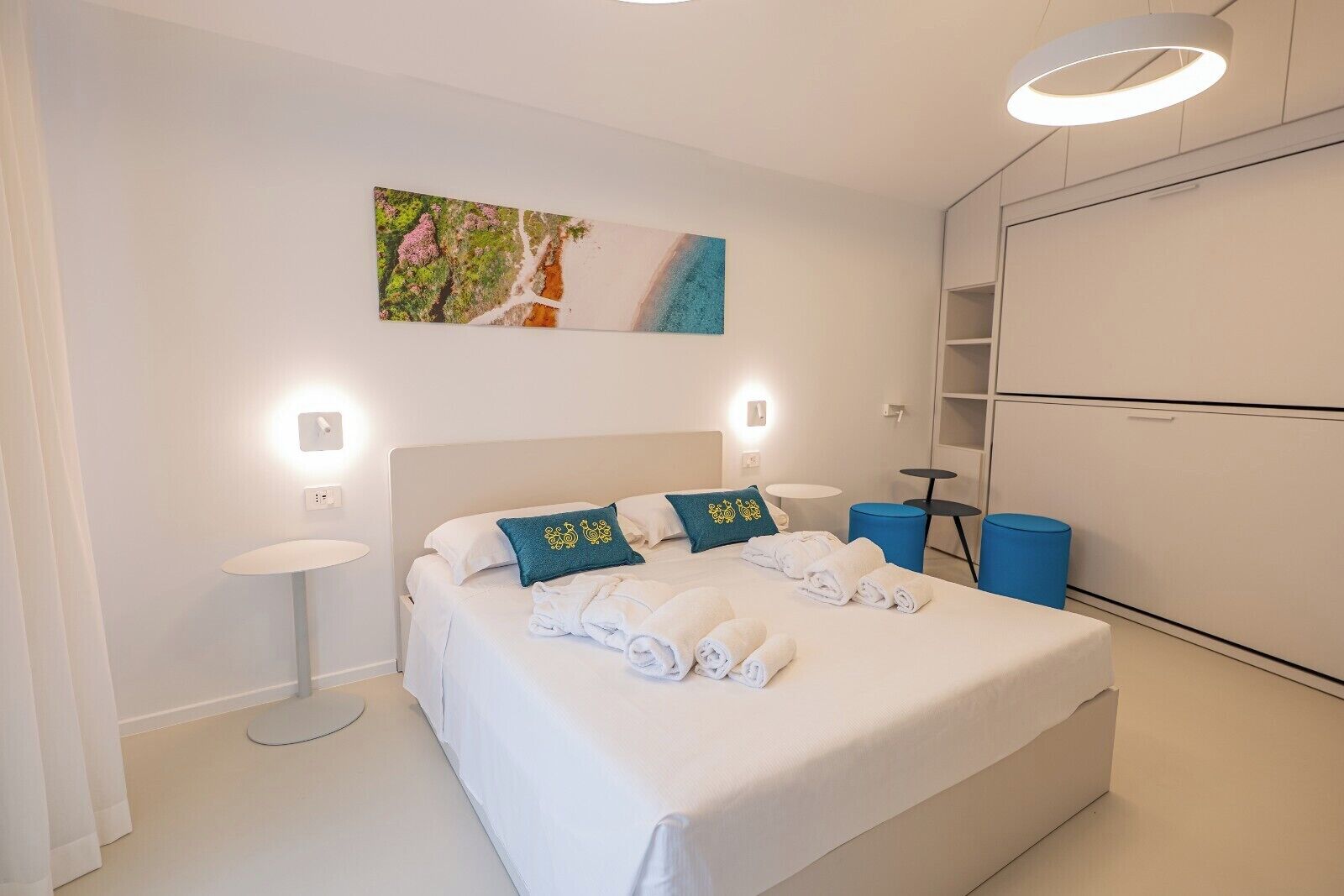 Ett modernt hotellrum med en stor säng, sängbord, en tavla och en garderob.