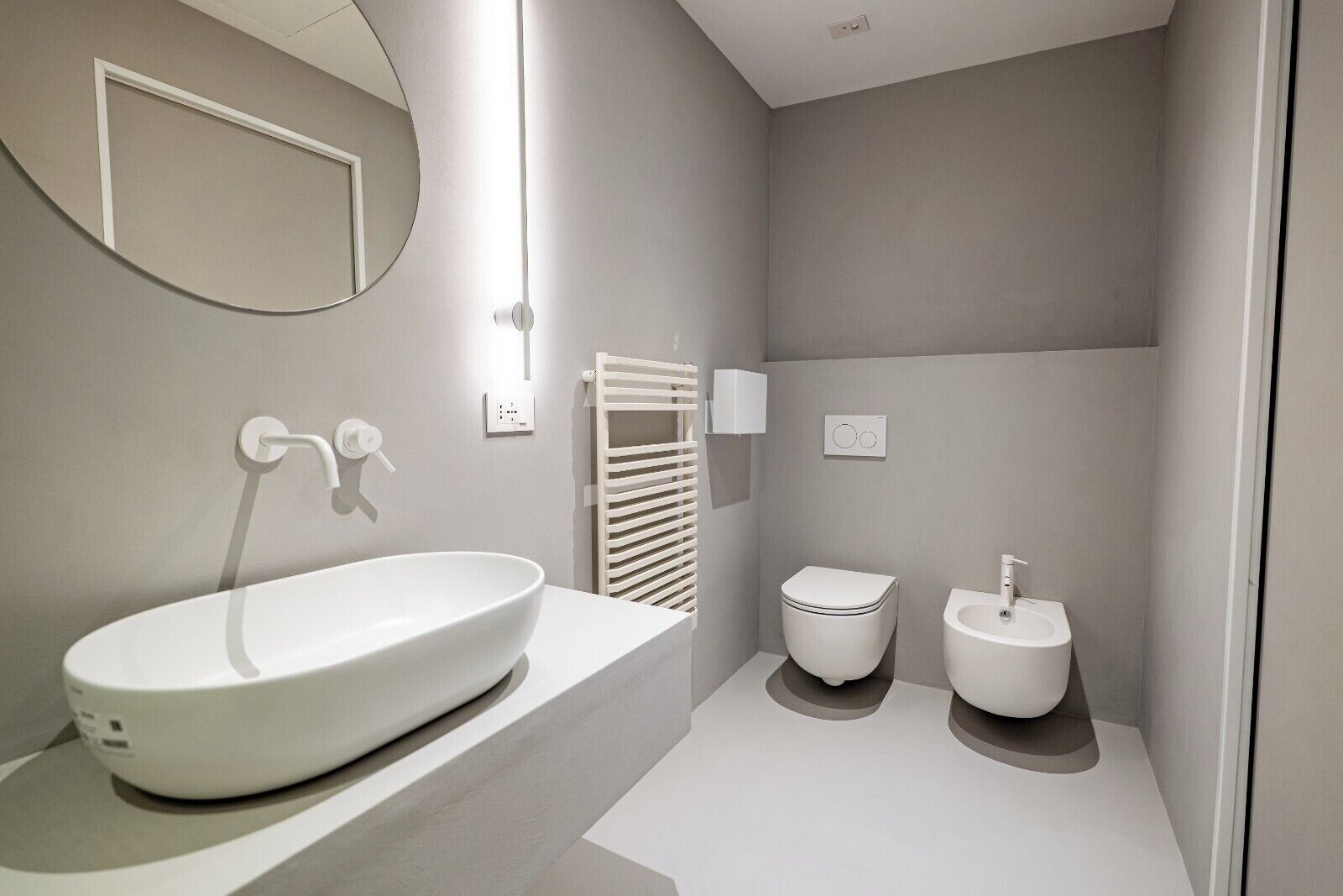 A modern bathroom with a large oval sink, a toilet, and a bidet.