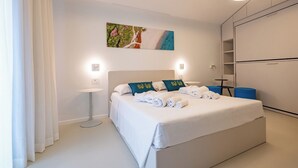A modern hotel room with a large bed, a bedside table, a wardrobe, and a painting on the wall.