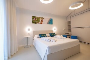 Ein modernes Hotelzimmer mit einem großen Bett, einem Nachttisch, einem Kleiderschrank und einem Bild an der Wand.