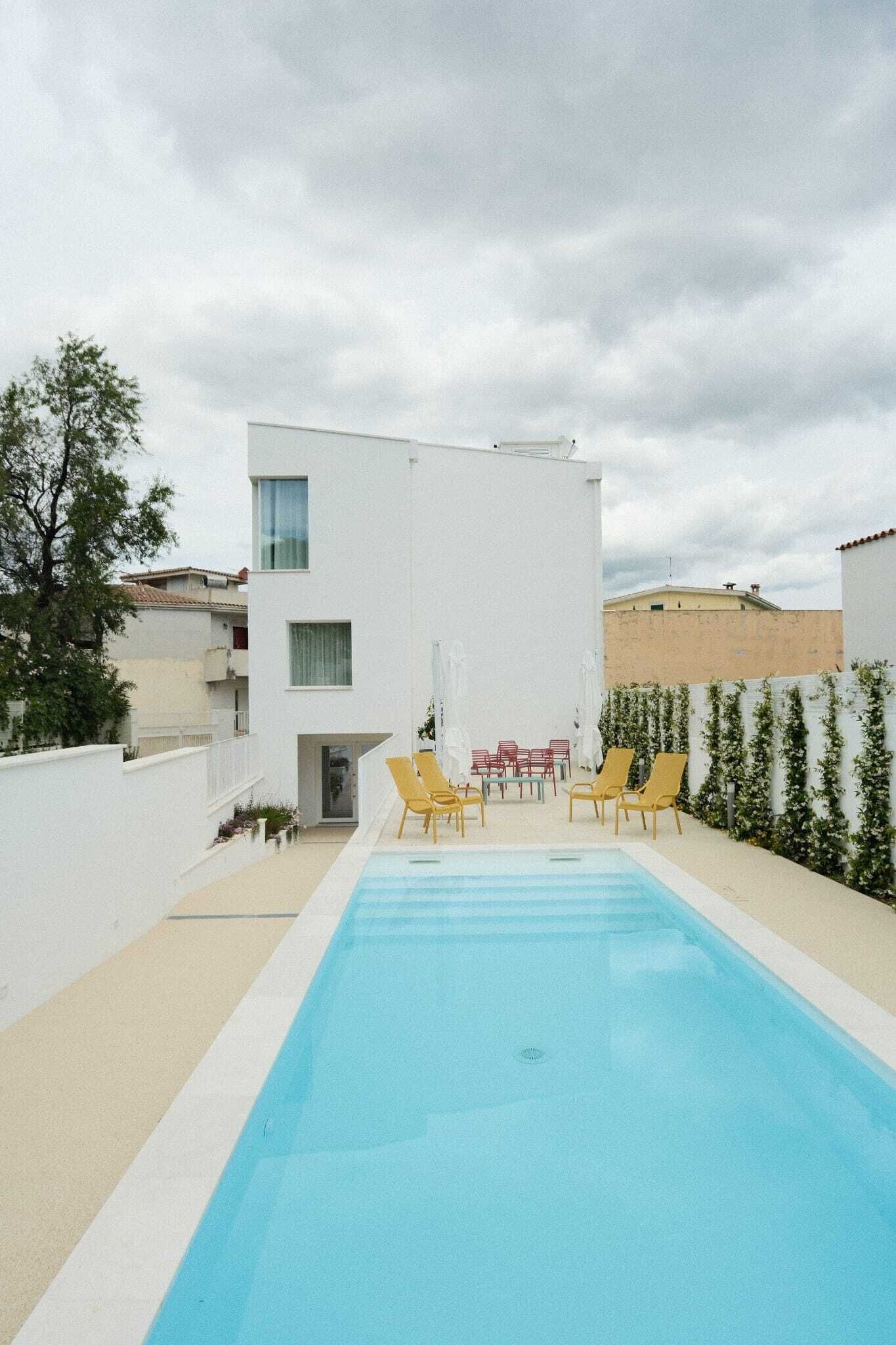 A modern building with a swimming pool, outdoor seating, and a white exterior.