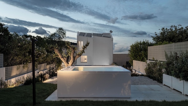 A modern building with a flat roof, a rectangular pool, and a well-maintained garden.