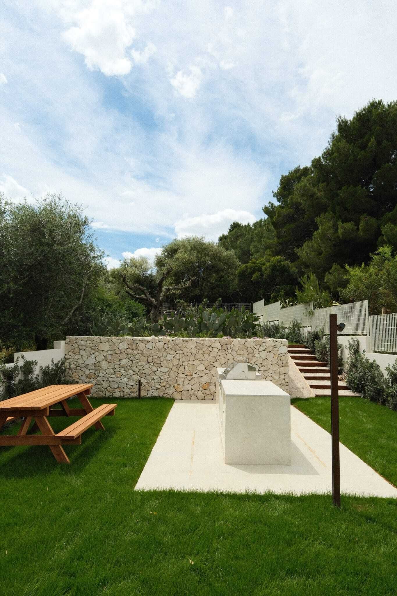 A patio area with a stone wall, a concrete seating area, and a wooden picnic table.