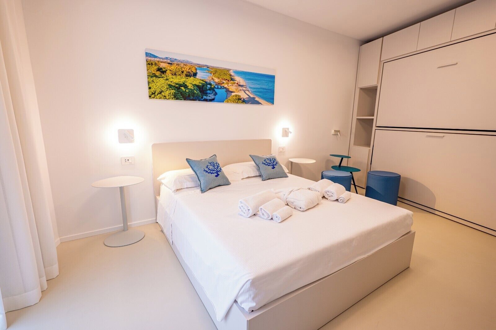Una habitación de hotel con cama, mesitas de noche, un cuadro y un armario.