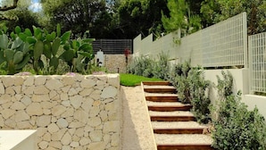 A stone wall, a grassy area, and a staircase leading up to a gate.