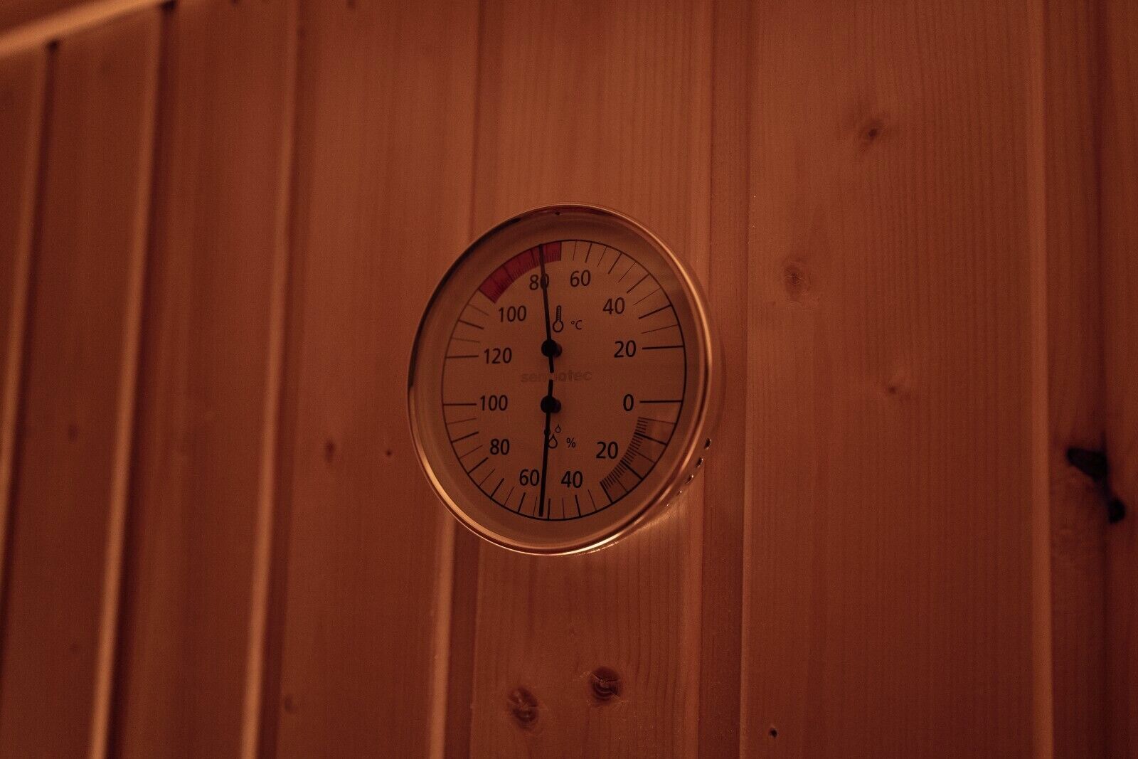 A thermostat mounted on a wooden wall.