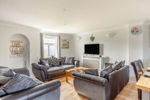 A modern living room with a sofa set, a coffee table, and a TV mounted on a white cabinet. - 4 bed Lodge Newquay Cornwall Holiday Park Sleeps 8 (Newquay)