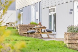 A house with a stone wall, a wooden bench, and a small garden area. - 4 bed Lodge Newquay Cornwall Holiday Park Sleeps 8 (Newquay)