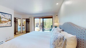Ein Hotelzimmer mit einem großen Bett, Blick ins Freie und einem gerahmten Bild an der Wand.