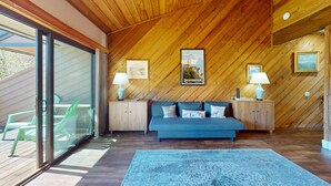 Ein Zimmer mit Holzboden, einem blauen Sofa, zwei Nachttischen mit Lampen und einem großen Fenster mit Blick.