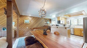 A modern kitchen with wooden cabinetry, a central island, and a hanging light fixture.