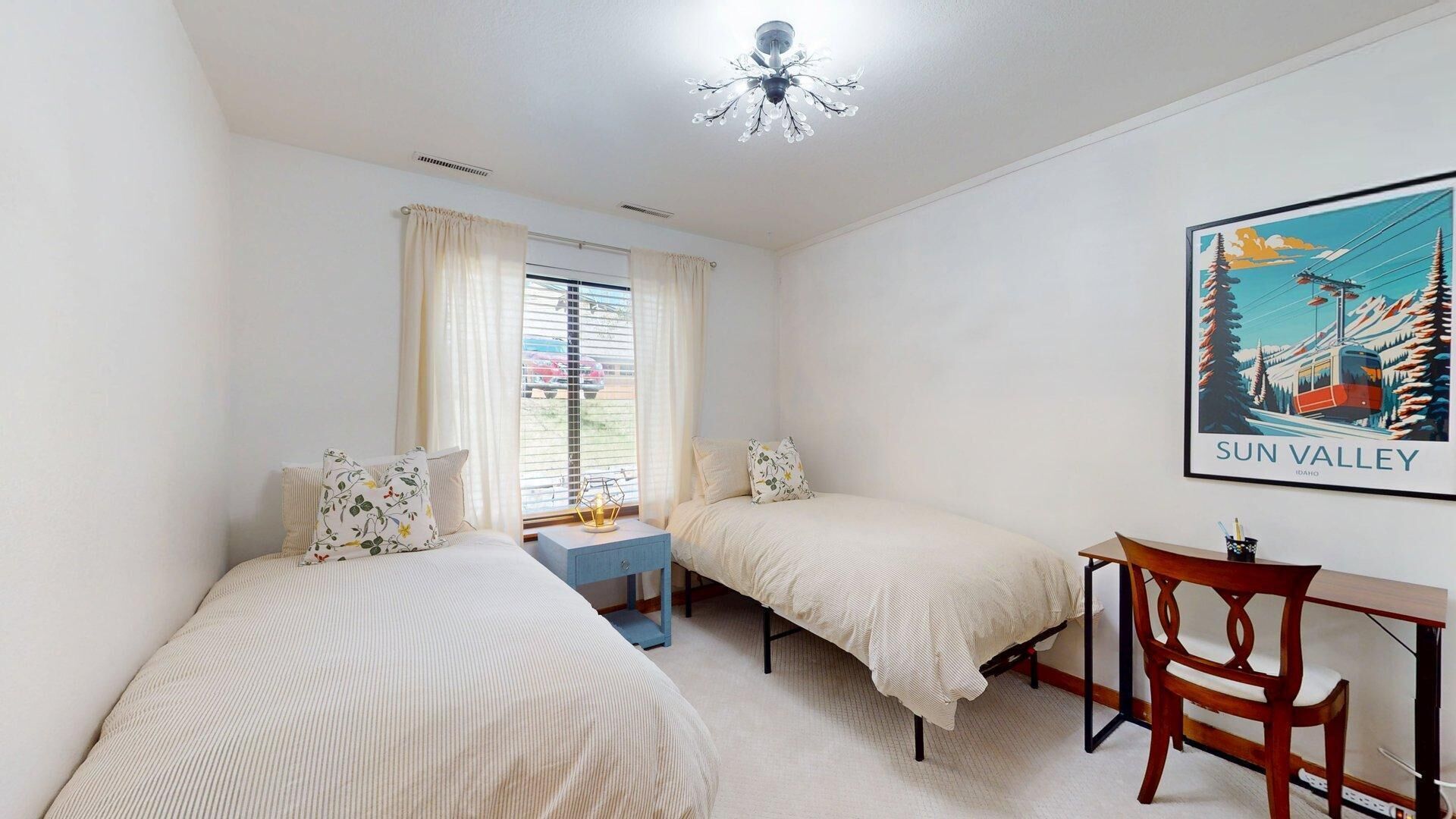 Quarto com duas camas, uma escrivaninha e uma cadeira.