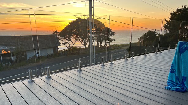 Eine Terrasse mit Feuerschale, mit Blick auf eine Straße und Bäume, im Hintergrund ein Sonnenuntergang.