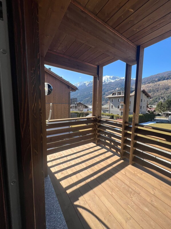Ein hölzerner Balkon mit Blick auf schneebedeckte Berge und einen klaren Himmel.