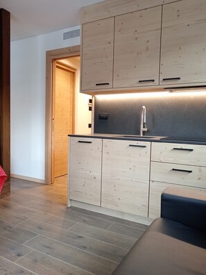 A modern kitchen with wooden cabinets, a stainless steel sink, and a built-in oven.