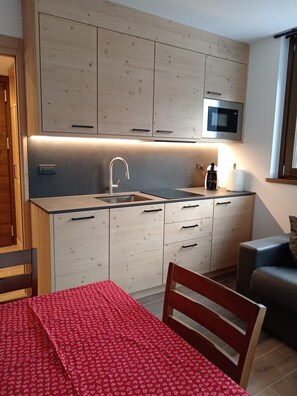 A compact kitchen with a built-in microwave, a sink, and wooden cabinets.