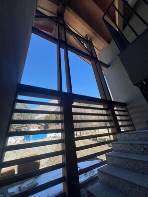 Una escalera con vistas a un paisaje nevado a través de una ventana con persianas horizontales.
