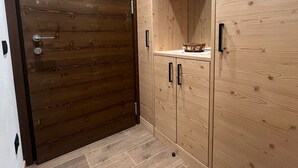 Una habitación con puerta de madera, un armario de dos puertas y suelo de baldosas.