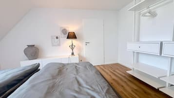 A bedroom with a bed, bedside table, lamp, and a white wardrobe.