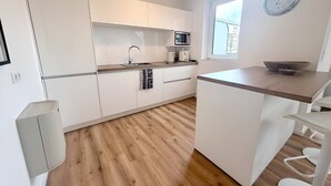 A modern kitchen with white cabinetry, a microwave, and a window.