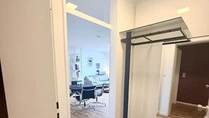 A hallway with a wooden floor, a bench, and a door leading to a room with a bed and a desk. - City-Loft Lingen Apartment 3 in the heart of Lingen (Lingen (Ems))