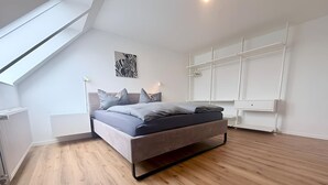 A modern bedroom with a sloped ceiling, a bed with grey bedding, a zebra artwork on the wall, and built-in white shelving. - City-Loft Lingen Apartment 3 in the heart of Lingen (Lingen (Ems))