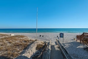 Ein Strand mit einer Holzpromenade, die zu einer Sitzgelegenheit führt.