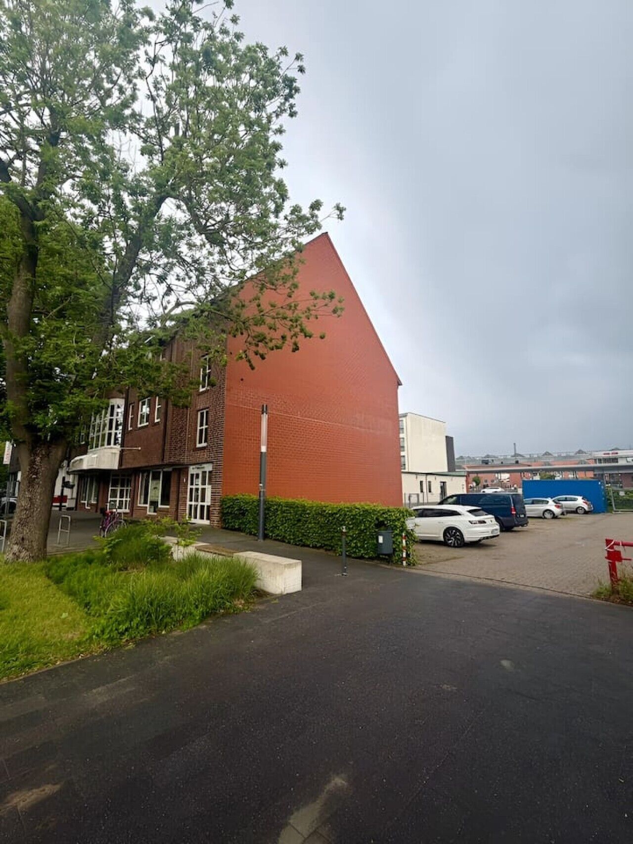 Ein Gebäude mit rotem Dach, Parkplatz und Baum.
