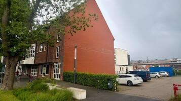 Ein Gebäude mit rotem Dach, Parkplatz und Baum.