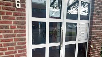 Ein Gebäudeeingang mit einer nummerierten Tür, Glasscheiben und einem Metallgriff.