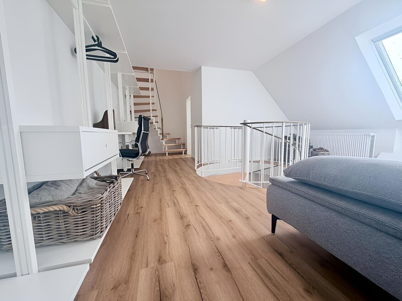 Um interior moderno com escadas, um sofá e um corrimão branco.