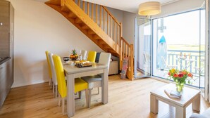 Un comedor con una escalera de madera, una mesa con sillas y vistas al exterior.