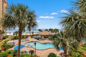 Un complexe hôtelier doté d’une piscine, offrant une vue sur la plage et bordé de palmiers.