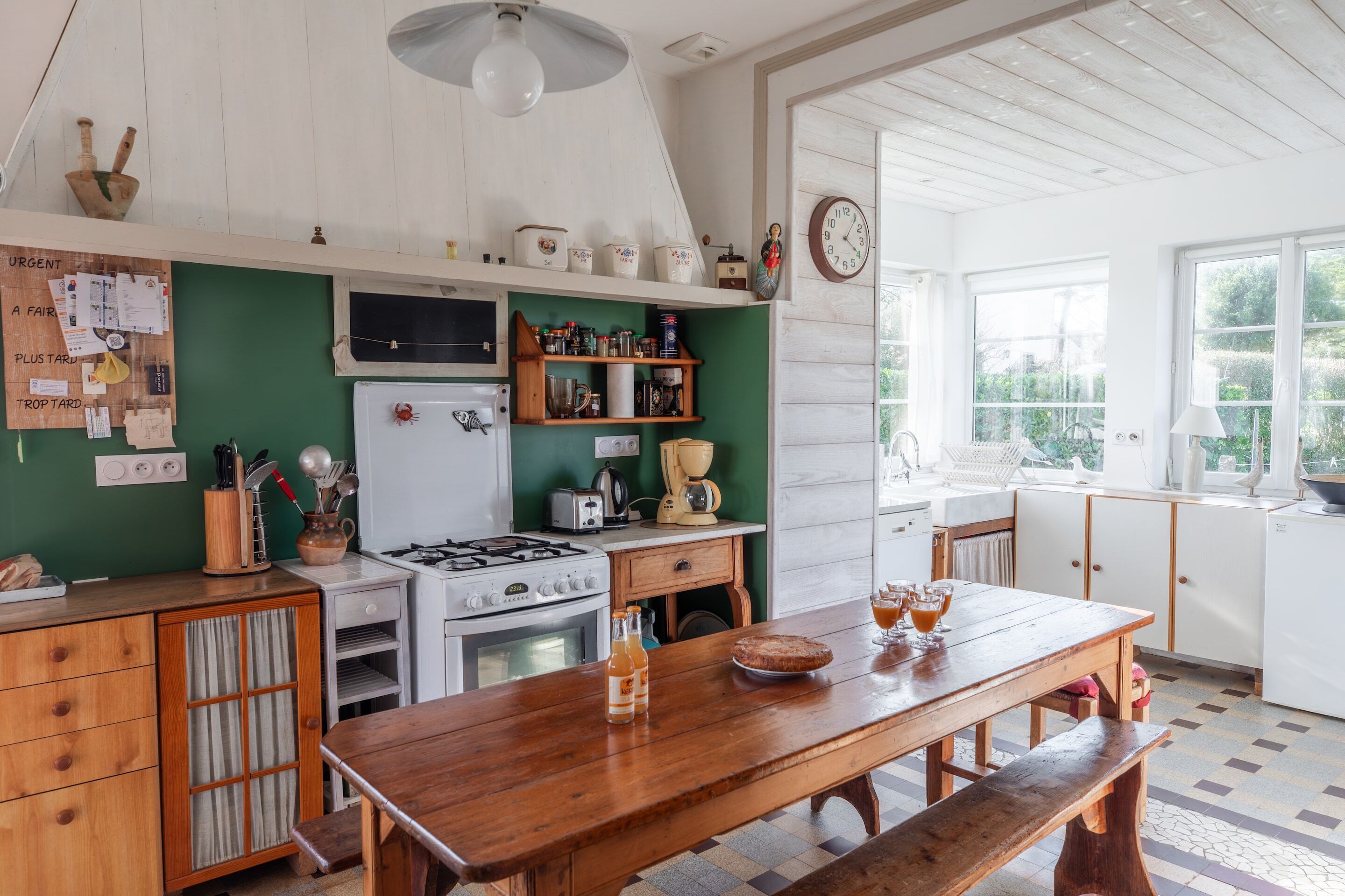 Een keuken met een houten tafel, een fornuis en diverse keukenapparaten.